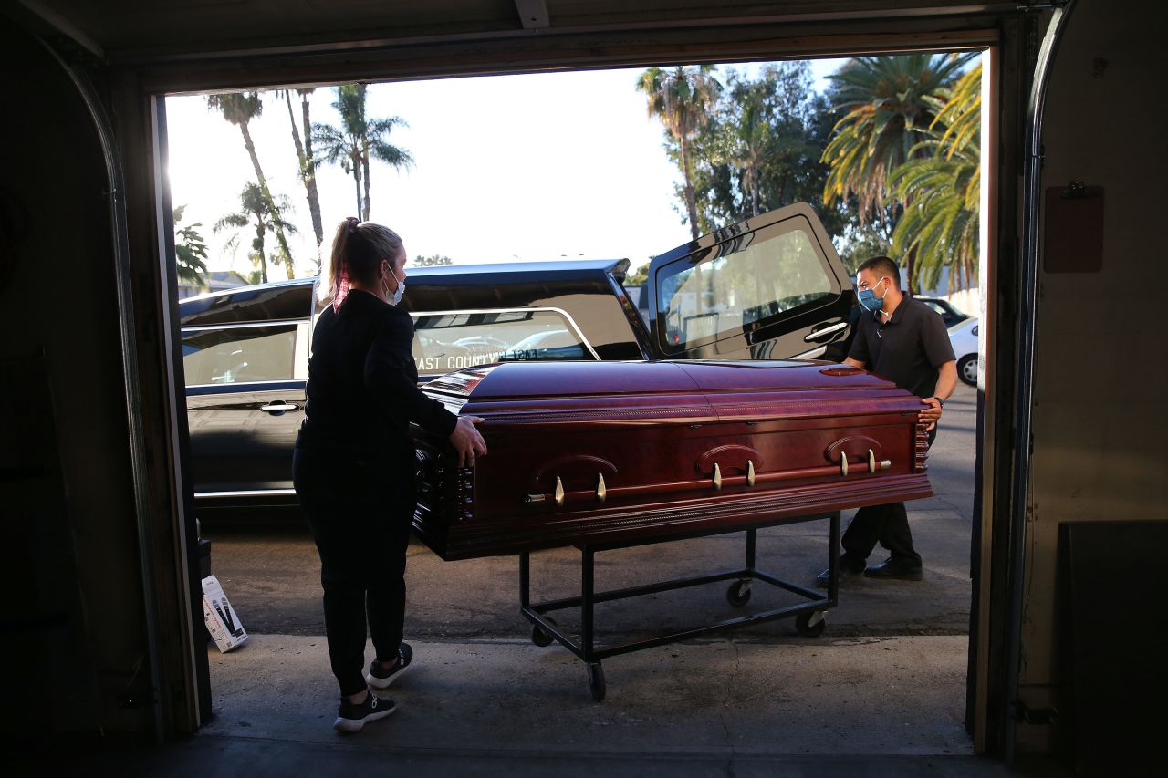 Funeral director Kristy Oliver and funeral attendant Sam Deras load the casket of a person who died after contracting Covid-19 into a hearse at East County Mortuary on January 15 in El Cajon, California