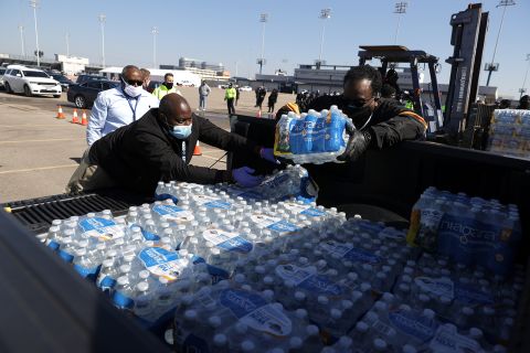 Volunteers load cases of water into the bed of a truck during a mass water distribution at Delmar Stadium on February 19 in Houston.