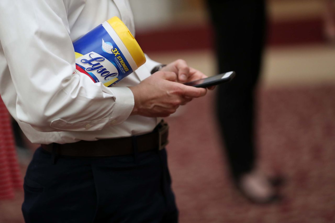A press briefing attendee holds a container of Lysol disinfecting wipes at San Francisco City Hall on March 16.