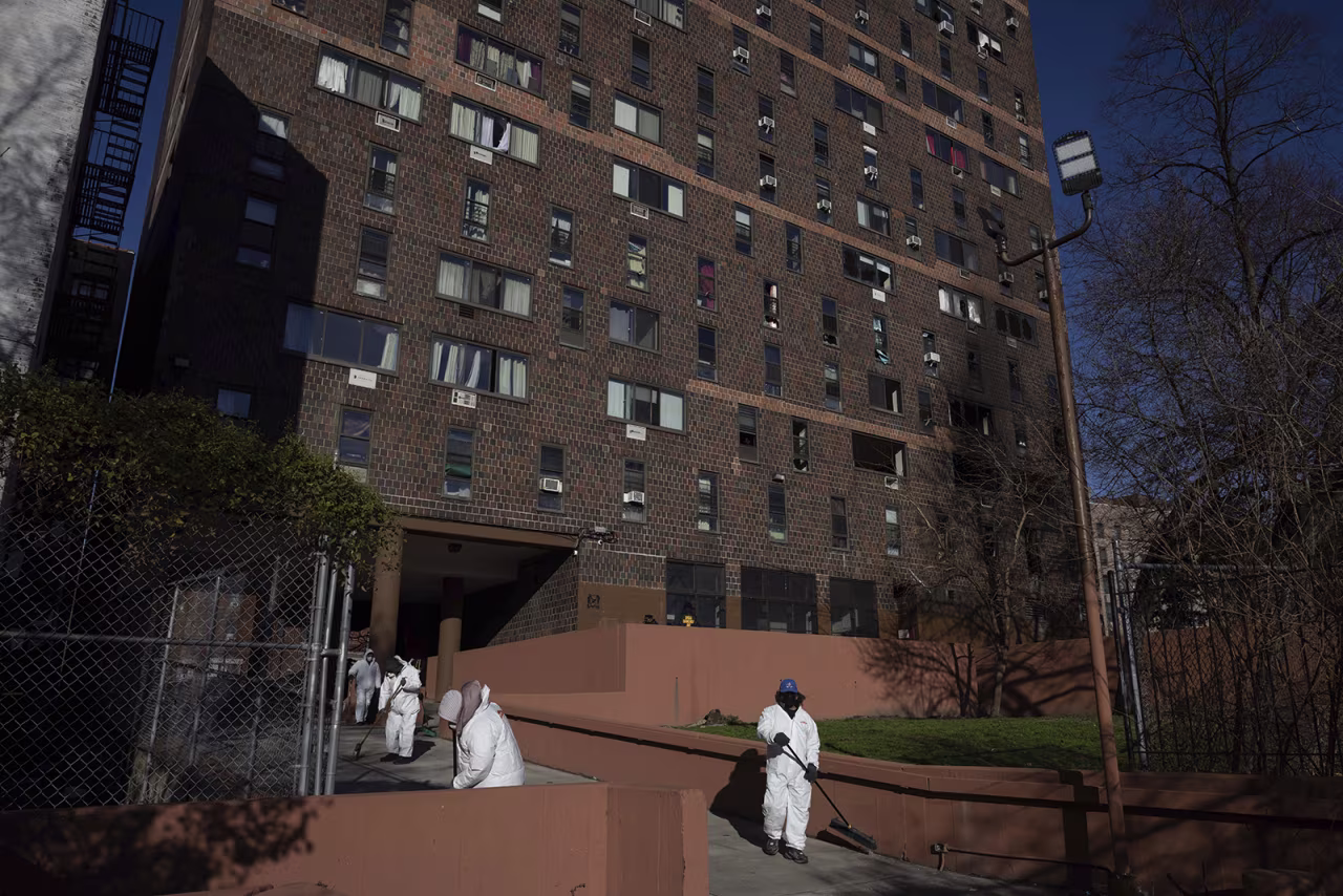 Cleaning and recovery crews work outside the apartment building in the Bronx on Monday.