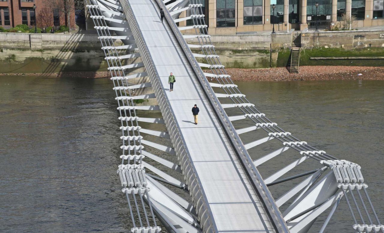 Pedestrians cross a quiet Millennium Footbridge across the River Thames in London in the mid-morning on Tuesday, March 17.