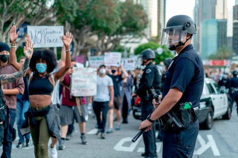 Protesters march past LAPD officers during a demonstration over the death of George Floyd, in downtown Los Angeles, California, on June 6.