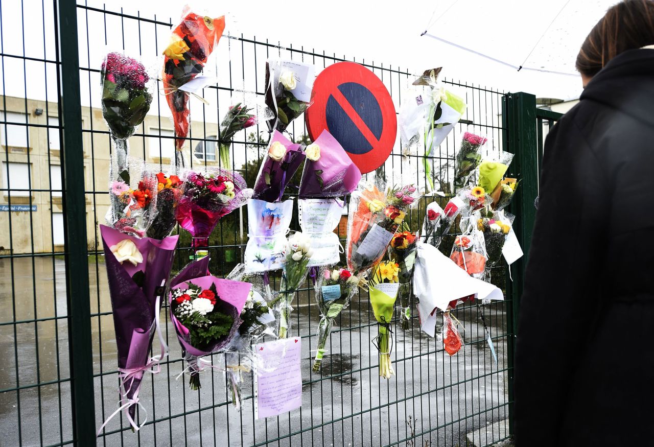 Flowers and letters are placed at the entrance of La Fontaine College in Crepy-en-Valois, France, on Sunday to honor a teacher who died as a result of coronavirus. 