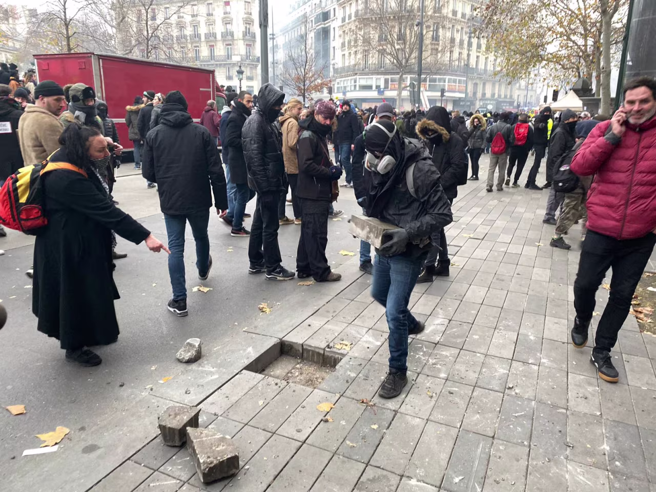 A protester rips up bricks from a sidewalk in Paris.