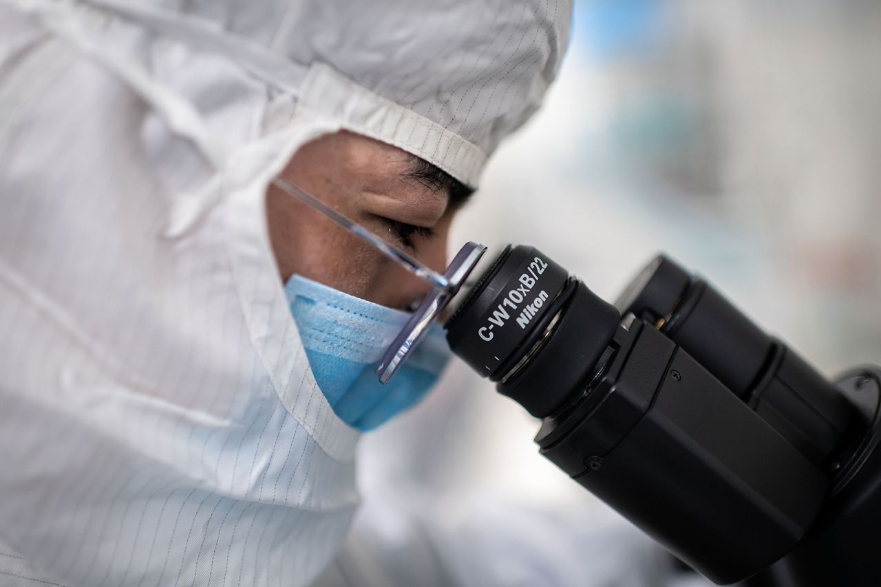 An engineer looks through a microscope as he checks tests on an experimental vaccine for Covid-19 at the Sinovac Biotech facilities in Beijing on April 29.