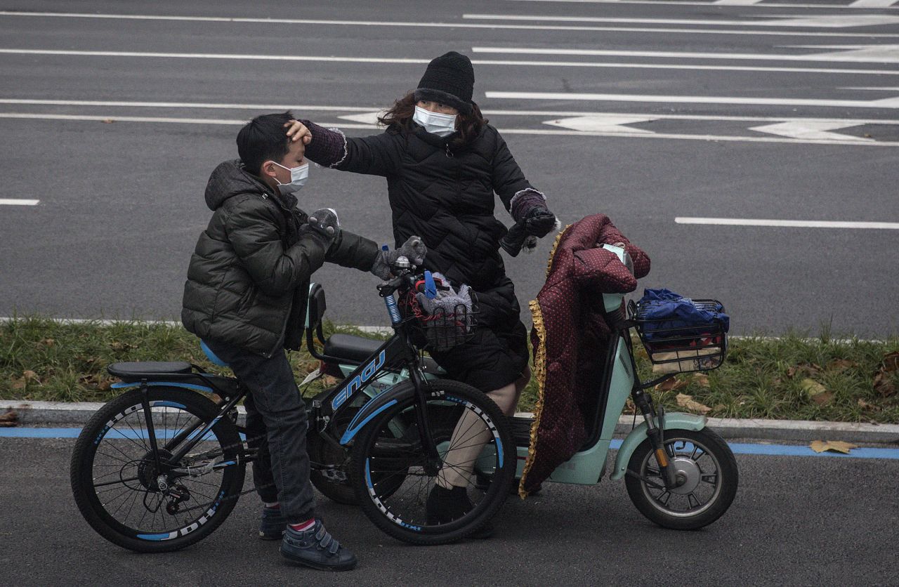 A woman checks her son's forehead on January 27, 2020 in Wuhan, China. The city remains on lockdown for a fourth day.