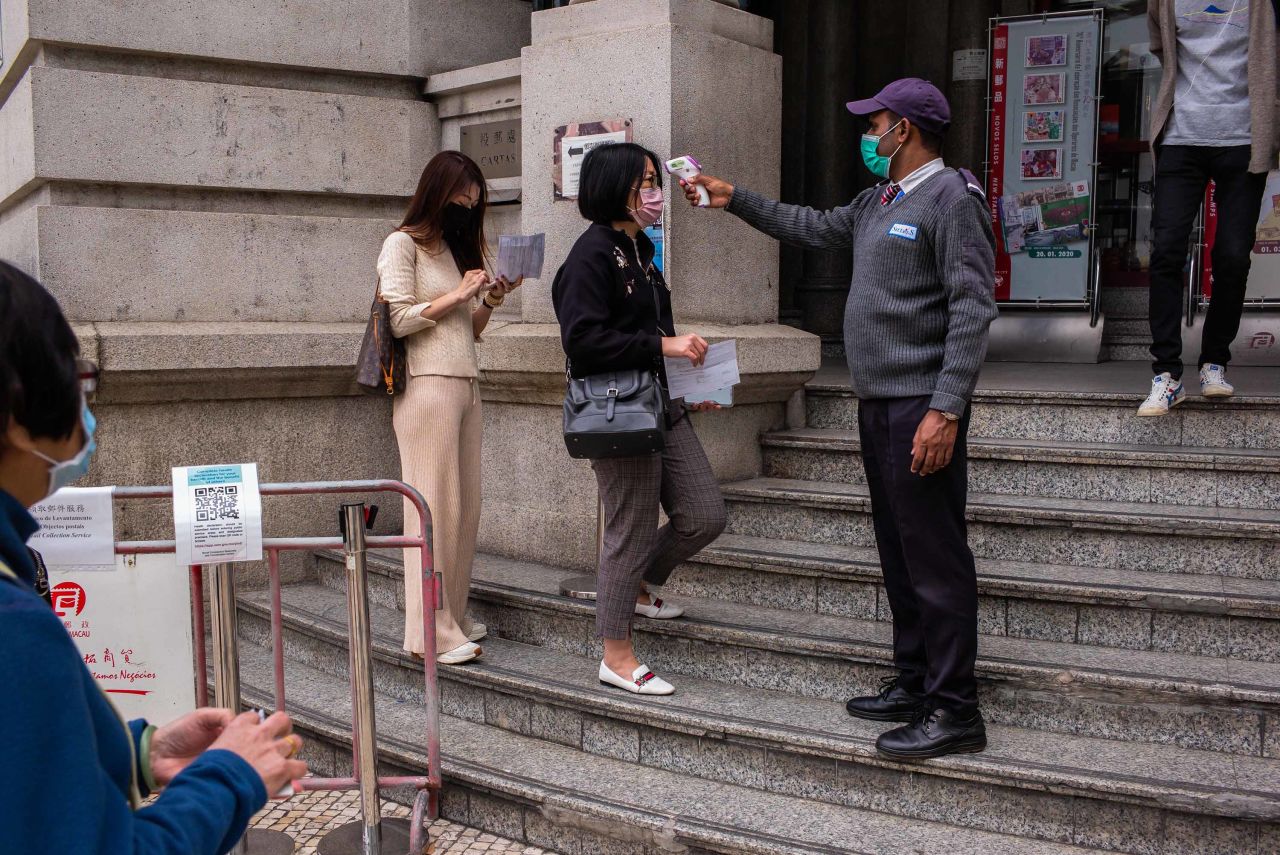 An official checks the temperature of visitors before they enter a government office in Macao on March 3.