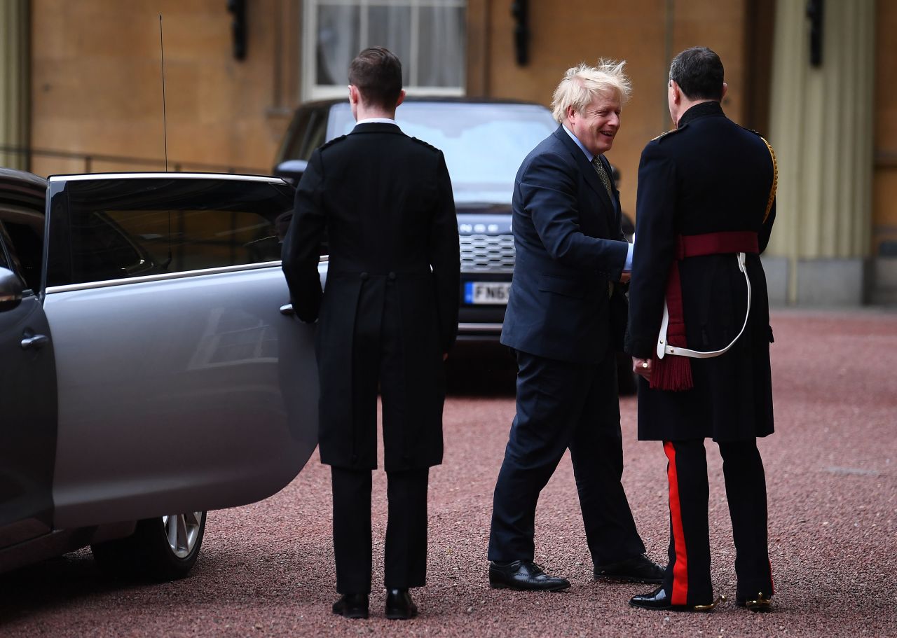 Boris Johnson greets courtiers as he arrives at Buckingham Palace.