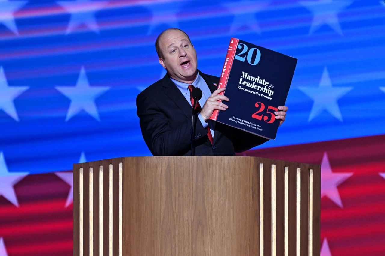 Colorado Governor Jared Polis holds a copy of the Heritage Foundation's "Mandate for Leadership," a major component of the "Project 2025" political initiative during the DNC in Chicago, on Wednesday August 21.