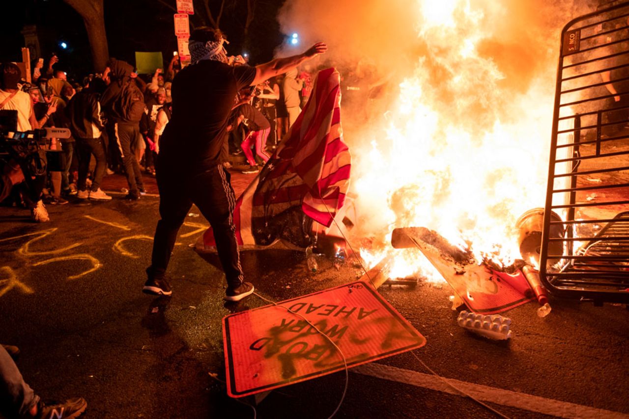 A protester throws a US flag into a burning barricade during a demonstration against the death of George Floyd near the White House on May 31, in Washington.