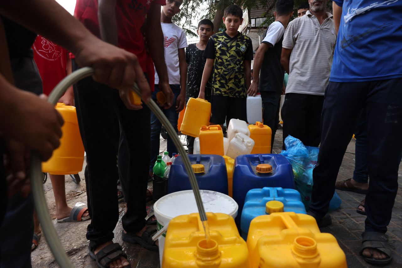 Palestinians queue to refill on water in Rafah refugee camp, in southern Gaza, on October 14, 2023.