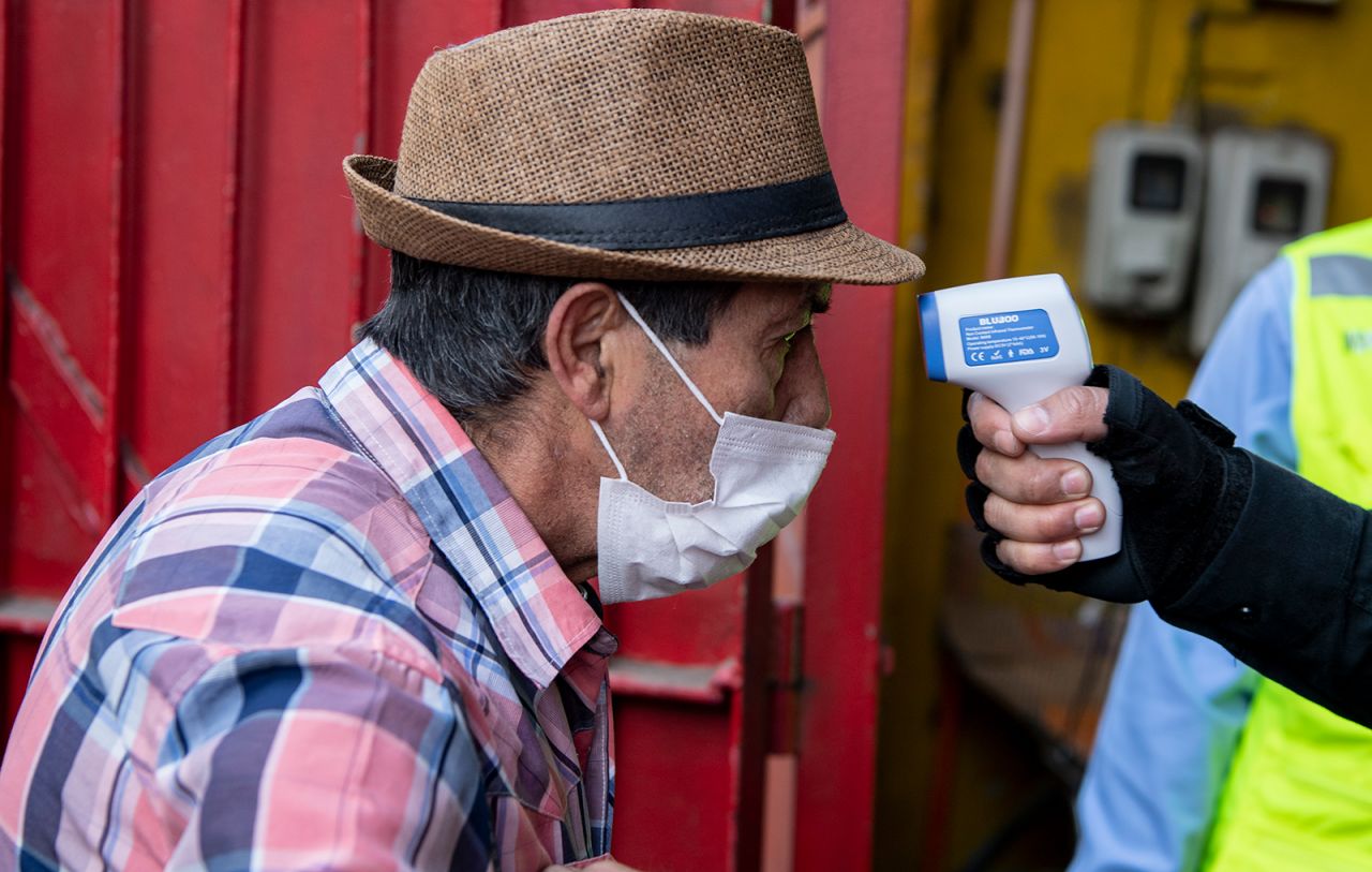 A security guard checks the body?temperature of a man wearing a face mask in Santiago, on Wednesday, May 6.