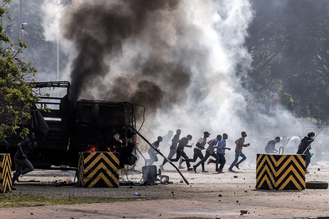 Protesters run to take cover outside the Kenyan Parliament after storming the building.