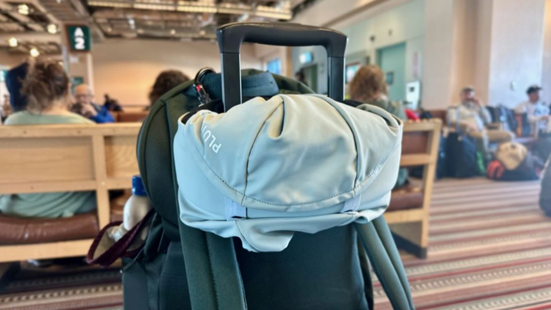 A photo of the Pluto Pod Travel Pillow attached to the handle of a carry-on suitcase