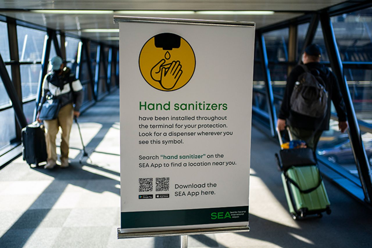 Travelers pass by a sign advertising hand sanitizer at Seattle-Tacoma International Airport on November 29, 2020 in SeaTac, Washington. 