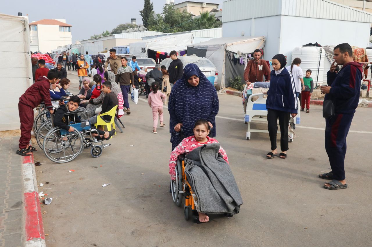 Noor Marouf, whose limb was amputated after being wounded in an Israeli strike, sits in a wheelchair as she is helped by her aunt at the European Hospital in Rafah, Gaza, on December 28.