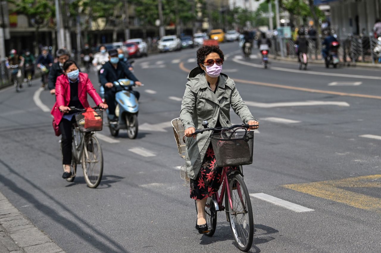 A woman wearing a face mask rides a bicycle on a street of Shanghai, China, on May 7.