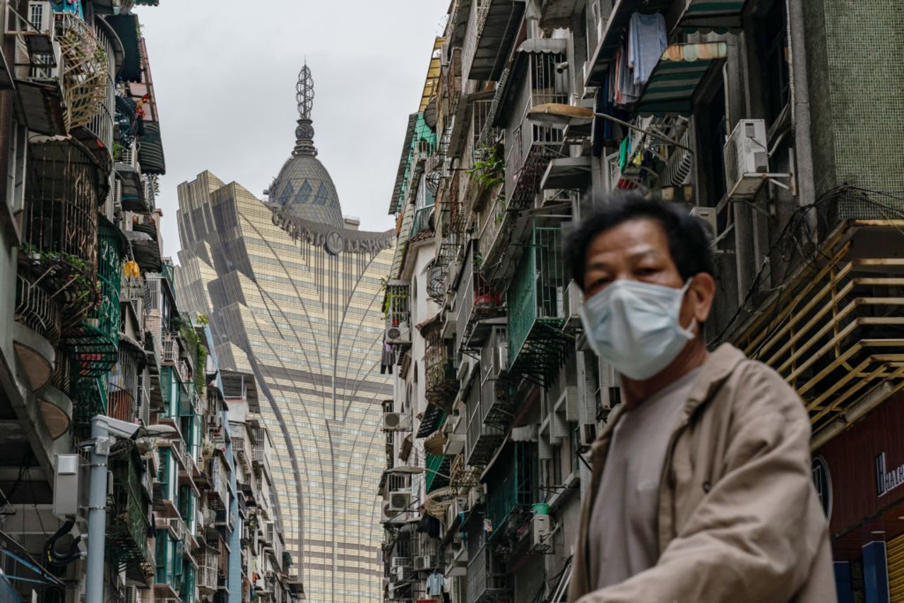 A man wearing a face mask walks across a street in front of the Grand Lisboa Hotel in Macau on February 5, 2020.