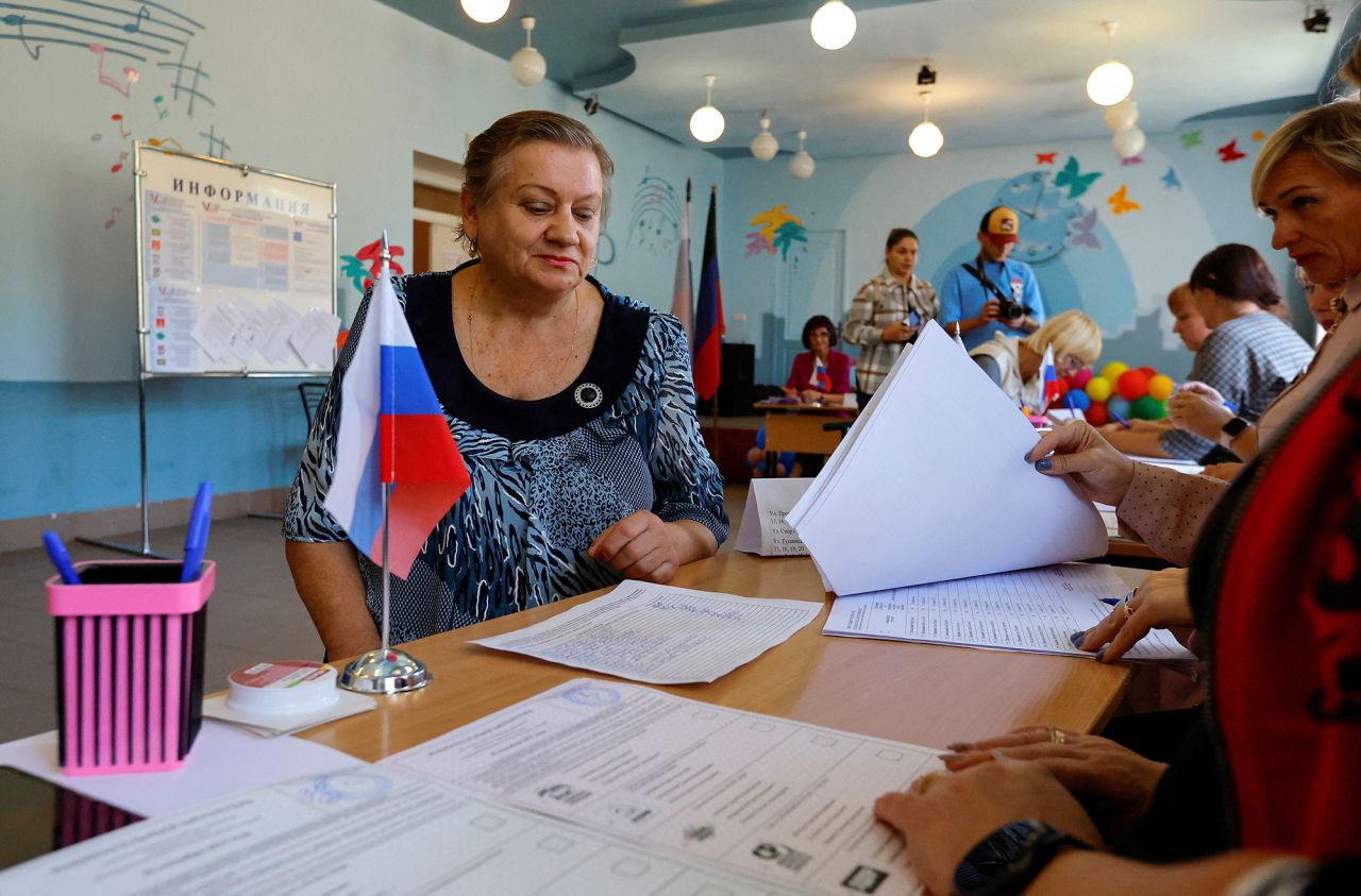 A voter sits in front of members of an electoral commission at a polling station during local elections held by the Russian-installed authorities in Donetsk, Russian-controlled Ukraine, on September 8.