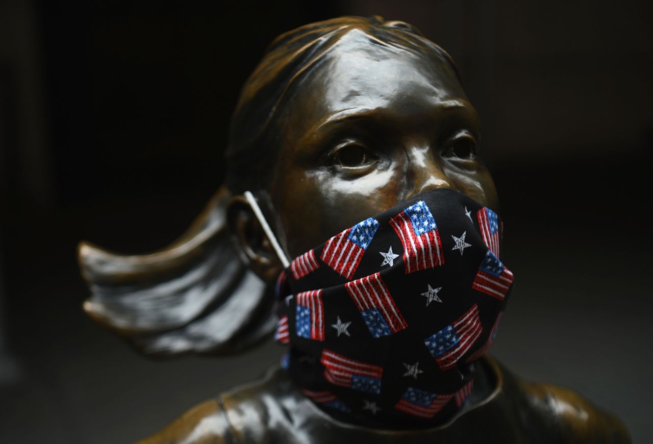 The "Fearless Girl" statue wears a face mask with American Flags outside the New York Stock Exchange at Wall Street on April 23, in New York City.