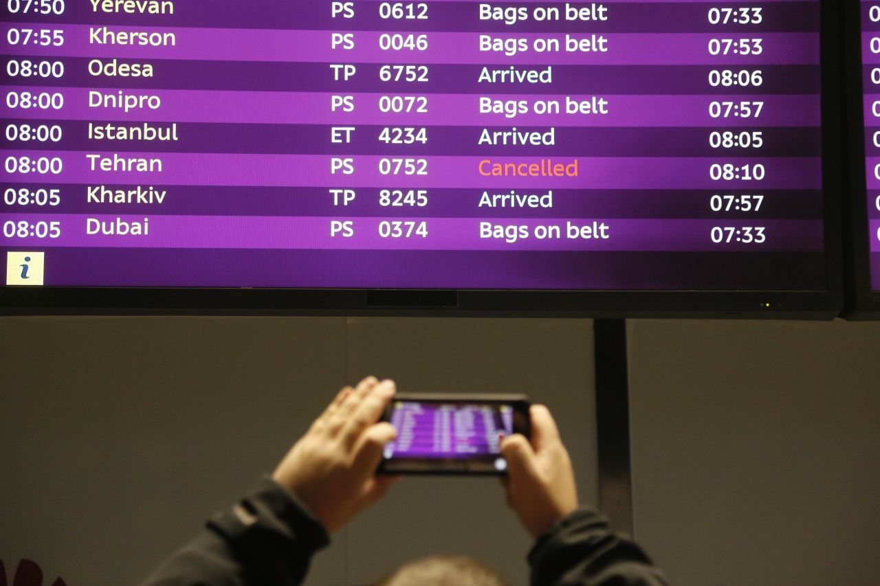 A man takes a photo of the arrivals board at Borispil International Airport outside Kiev, Ukraine, showing the cancelled fight from Tehran after it crashed on Wednesday.