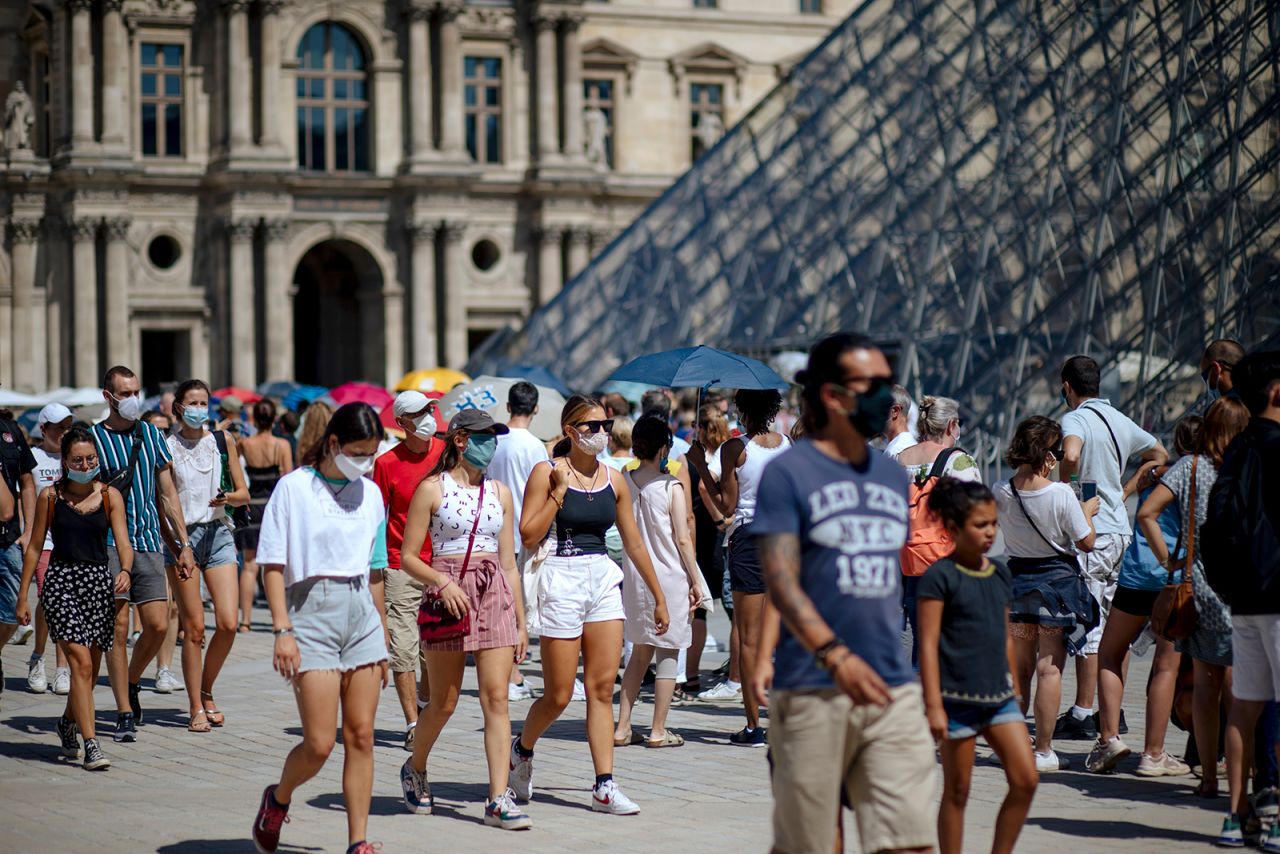 People walk past the Louvre Museum in Paris, on August 12.