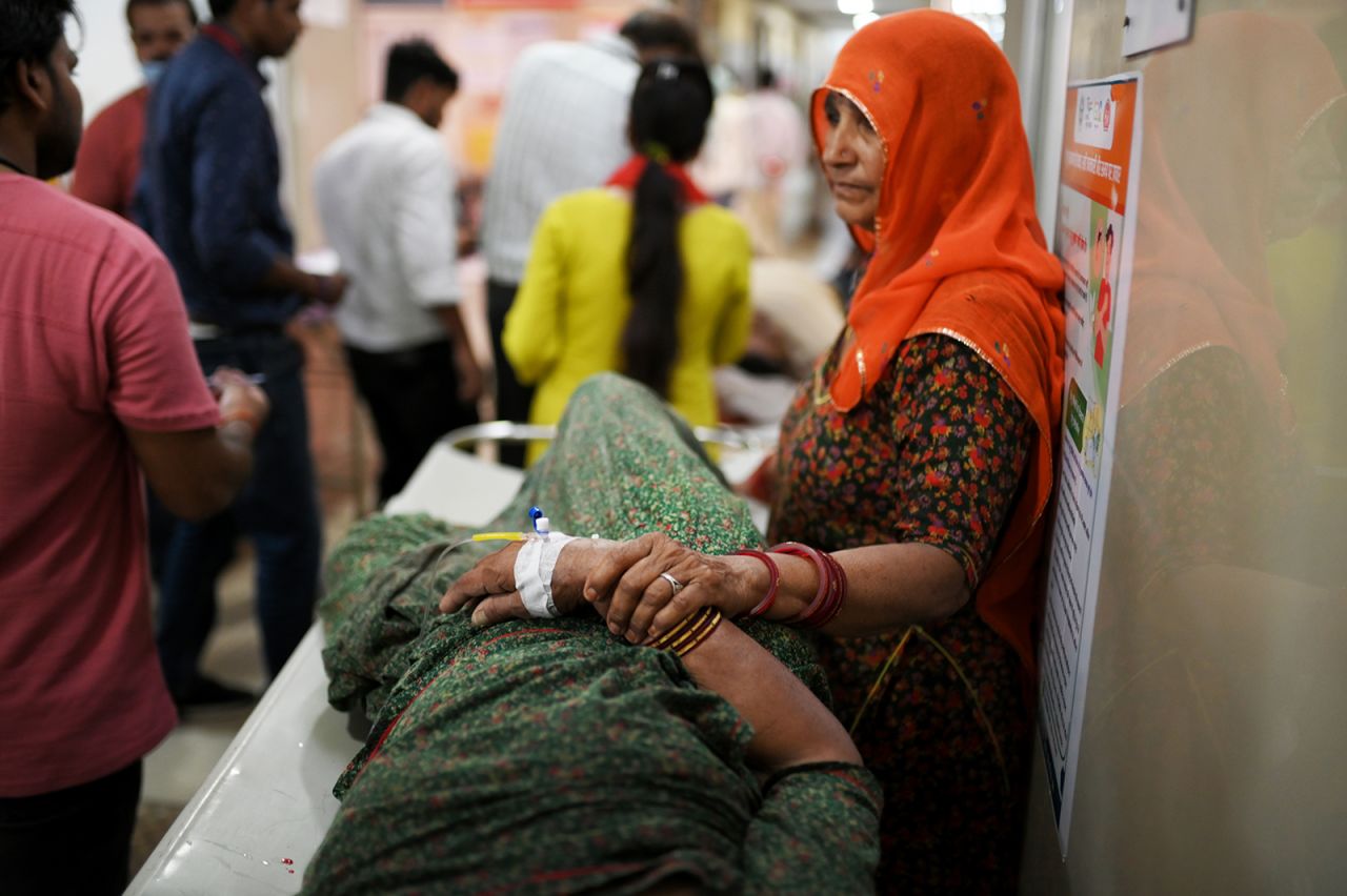 A woman is standing beside her family member who is suffering from heatstroke in Varanasi, India, on May 30.