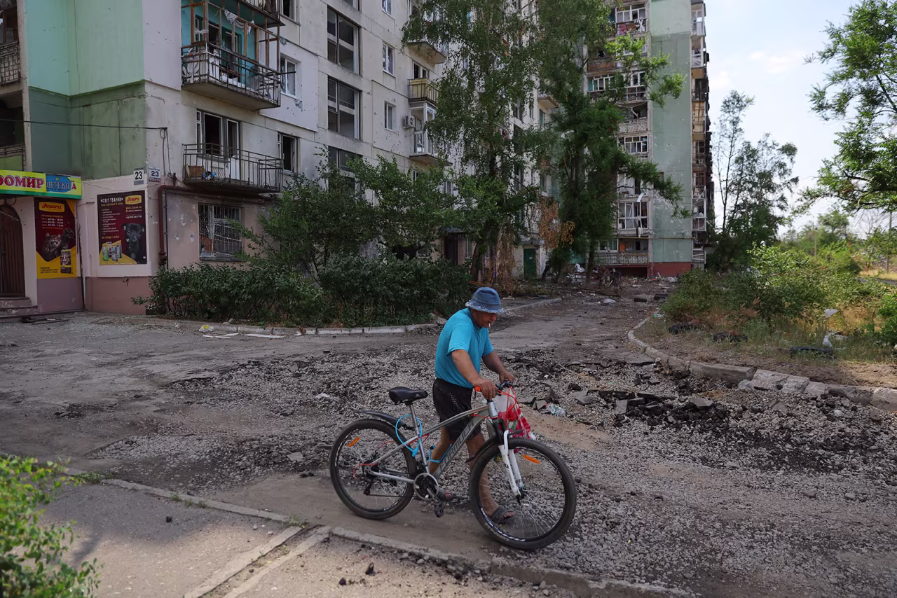 A resident walks a bike past a building in Severodonetsk on July 1.