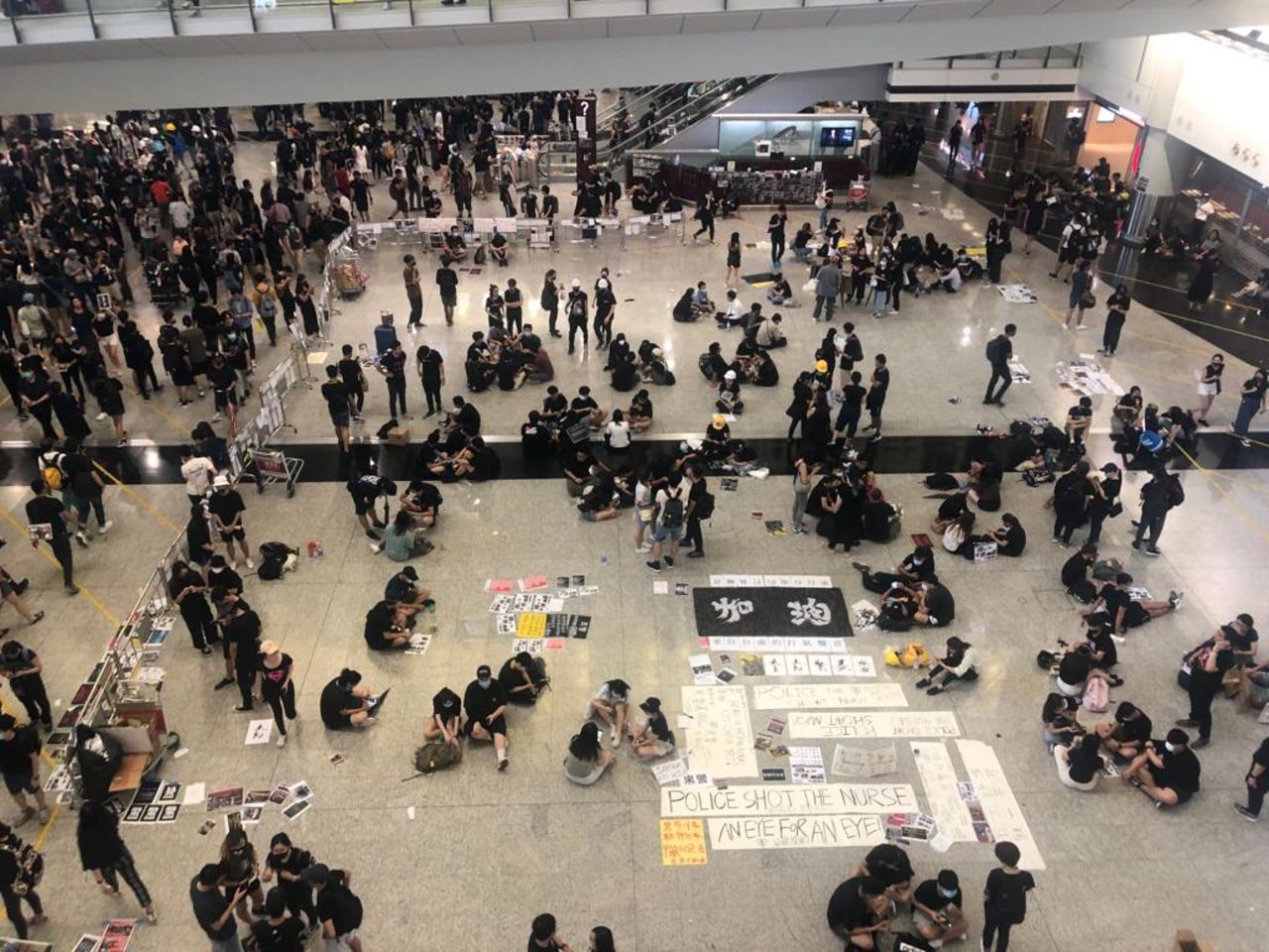 Protesters mill around in the airport, where they have conducted a sit-in for hours.