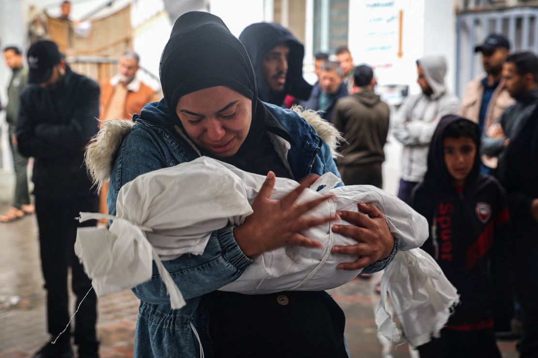 A woman mourns as she carries the shrouded body of a child killed following overnight Israeli strikes on Rafah on May 6. 