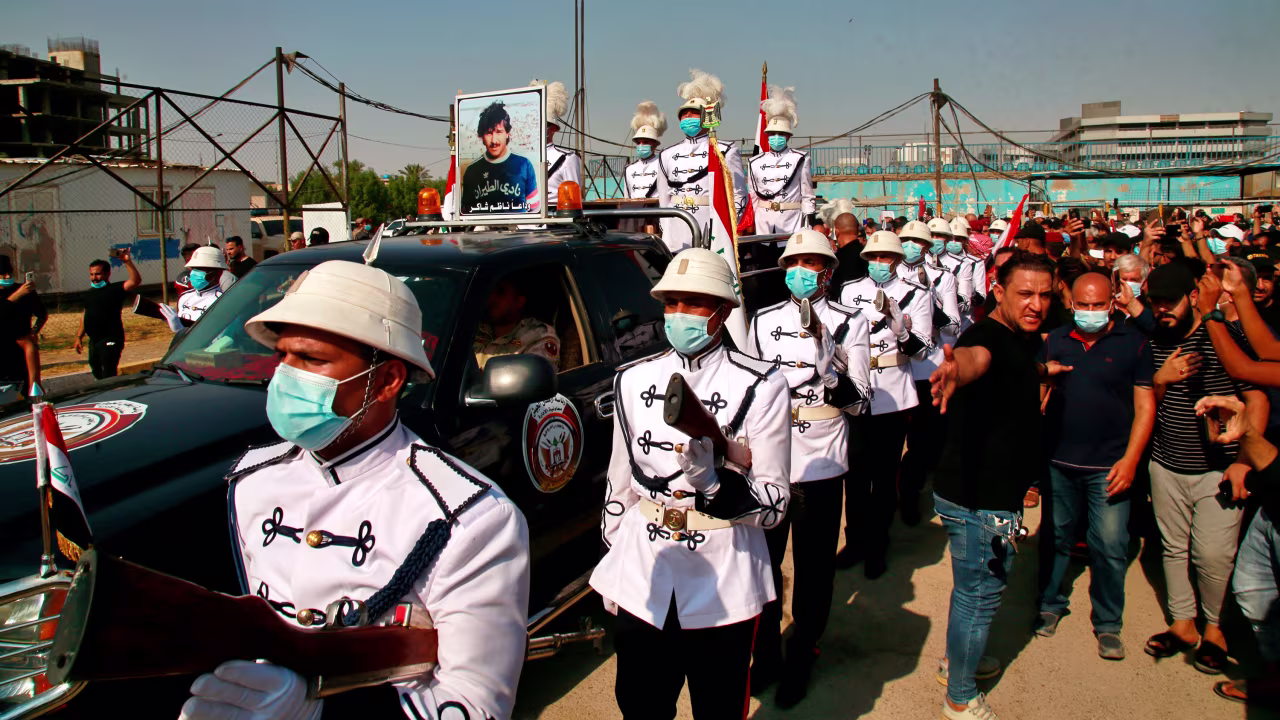 A military band and soccer fans escort the coffin of former Iraqi soccer star Nadhim Shaker during his funeral procession in Baghdad, Iraq, on September 12.