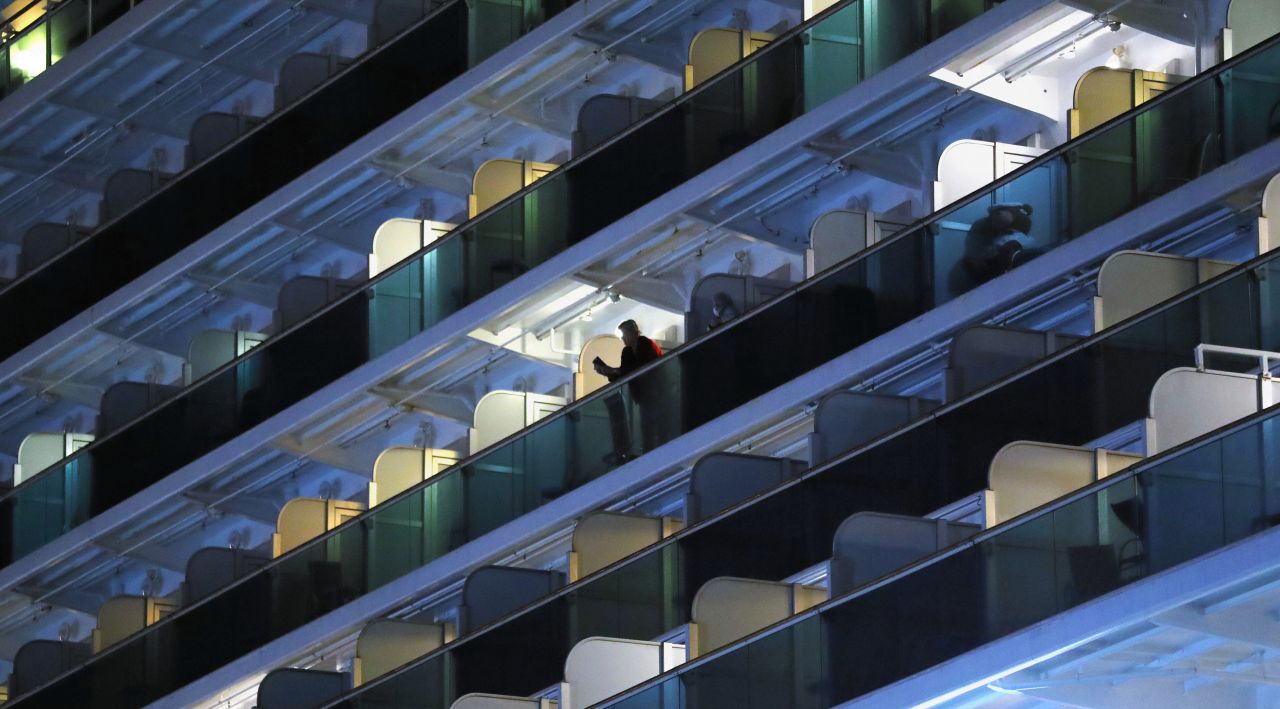 A passenger is seen at a balcony while clothes are hung on the Diamond Princess cruise ship on Friday.