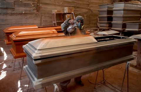 A factory worker applies the first coat of paint to a coffin in Lima, Peru, on May 29.