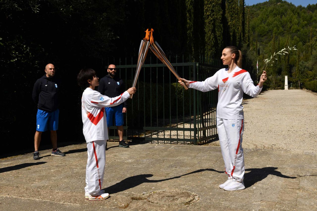 Torchbearer Anna Korakaki of Greece, right, passes the Olympic flame to Japan's Mizuki Noguchi during a lighting ceremony on March 12 in Olympia, Greece.