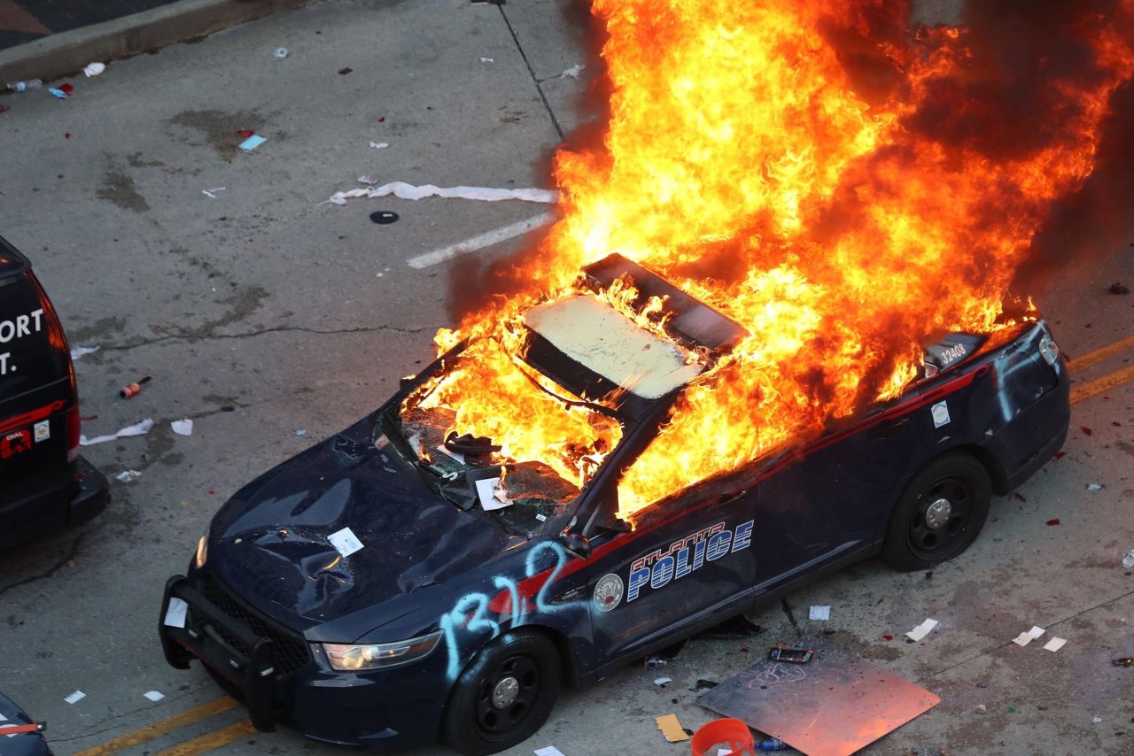 A police car burns after protesters marched to the Georgia State Capitol and returned to the area around the Centennial Olympic Park and CNN center in Atlanta, Gerpon Friday, May 29. 