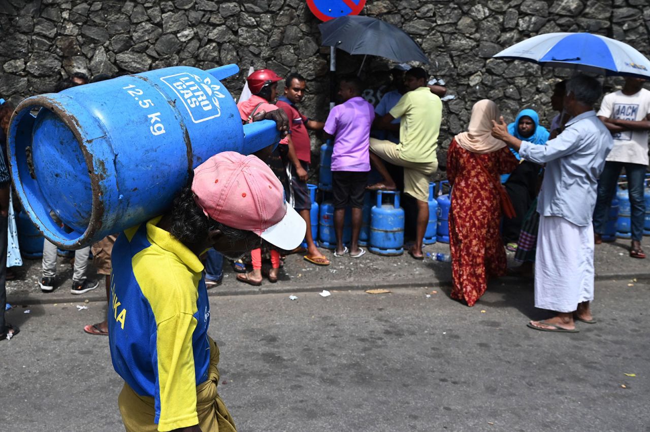 A man carries a Liquefied Petroleum Gas cylinder after collecting it at distribution point in Colombo, Sri Lanka, on July 12.