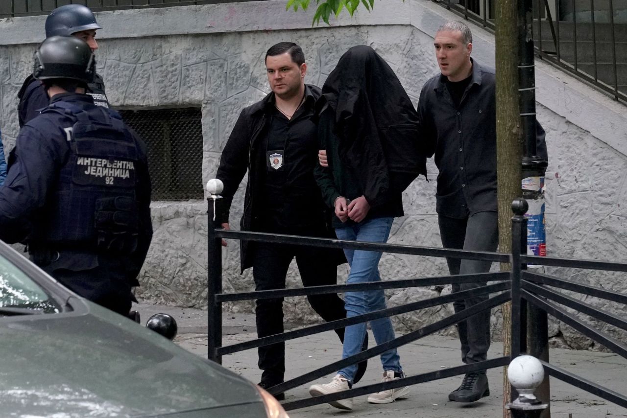 Police officers escort a person who is suspected of firing several shots at a school in the capital of Belgrade on Wednesday.