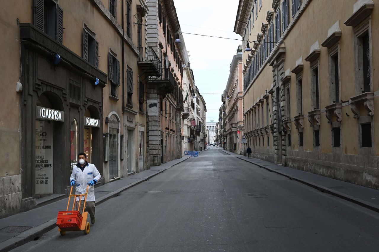 A delivery man wearing a protective mask pushes a cart across a deserted shopping street in Rome, Italy, on March 12.