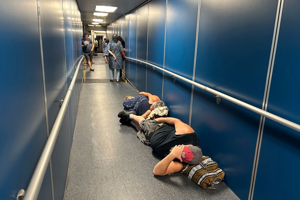 Travelers at Los Angeles International Airport sleep in a jetway for a delayed United Airlines flight to Dulles International Airport due to a widespread global outage early Friday, on July 19, in Los Angeles.