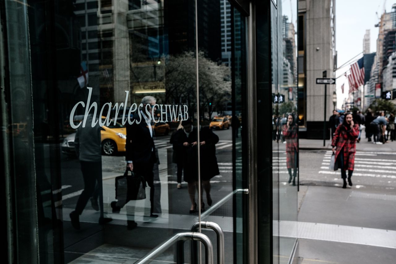 Pedestrians pass in front of a Charles Schwab Corp. office building in New York City in April 2018. 