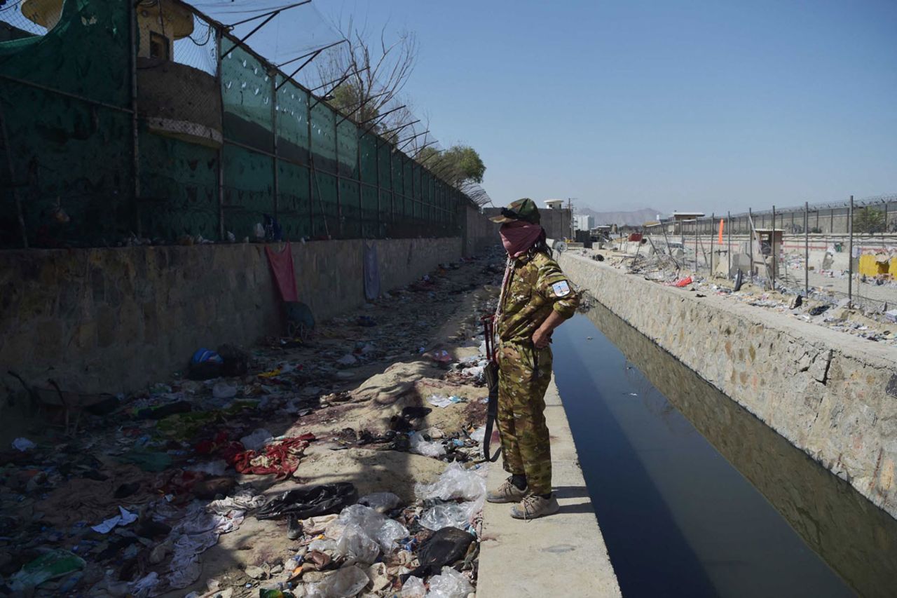 A Taliban fighter stands guard at the site of the attack, on August 27.