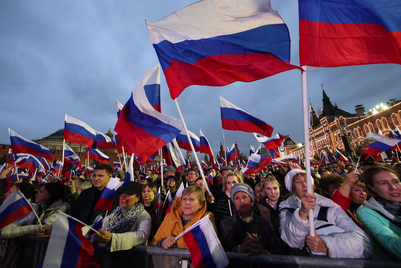 People wave Russian flags during the concert at the Red Square in Moscow on Friday, September 30.