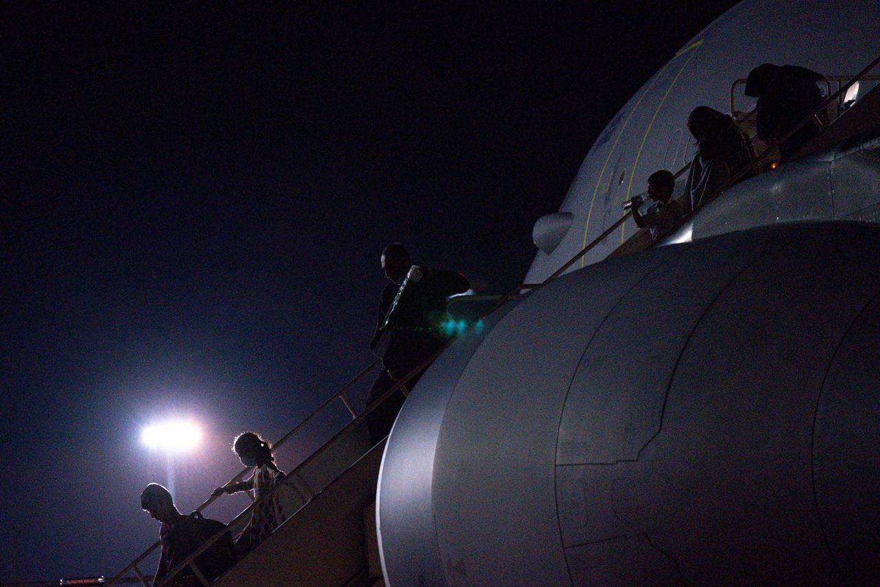 Passengers evacuated from Afghanistan disembark a British military transport aircraft at RAF Brize Norton station in southern England on August 26.