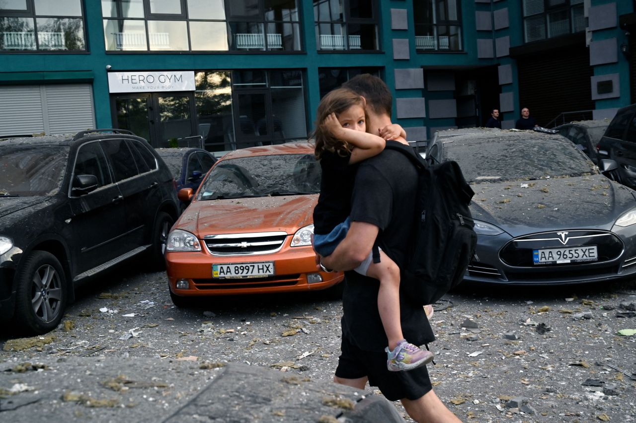 A local resident carries a girl outside a partially destroyed building as a result of missiles strikes in Kyiv, on June, 24.