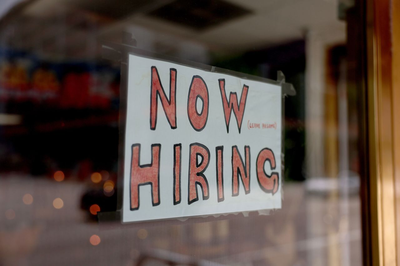 A 'Now Hiring' sign is posted on the window of a business looking to hire workers in Miami on May 5. 