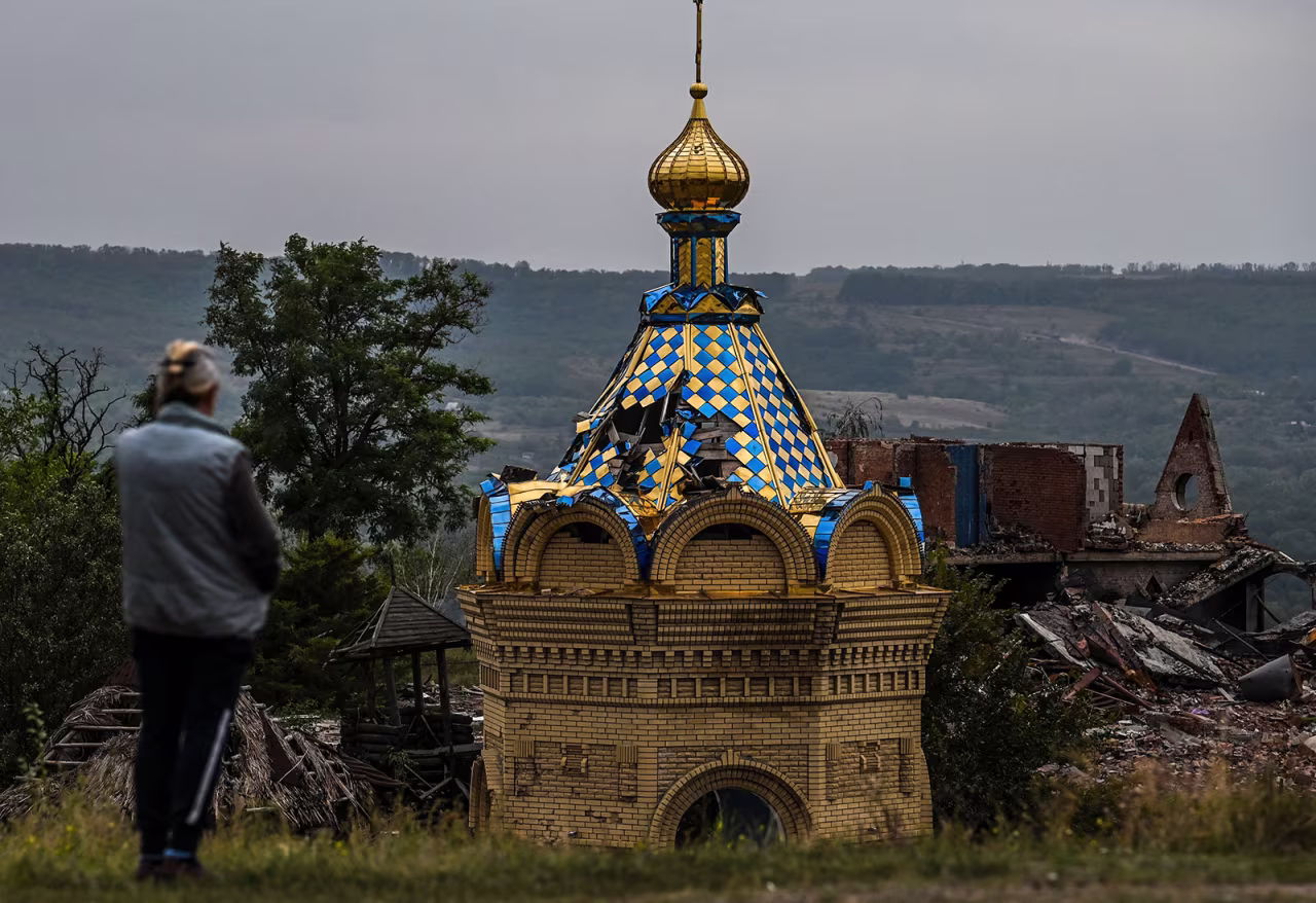A woman stands in front of a destroyed church in Izium, Kramatorsk, eastern Ukraine, on September 11, 2022.