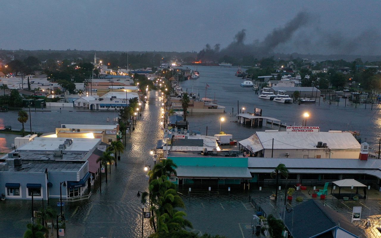 Smoke rises from a fire as flood waters inundate the downtown area of Tarpon Springs, Florida, on early Wednesday.