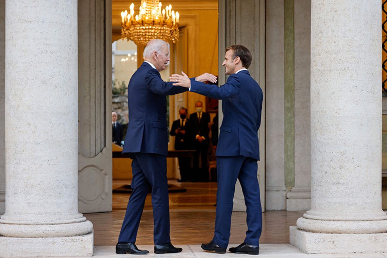 French President Emmanuel Macron (R) welcomes US President Joe Biden before their meeting at the French Embassy to the Vatican in Rome on October 29, 2021. 