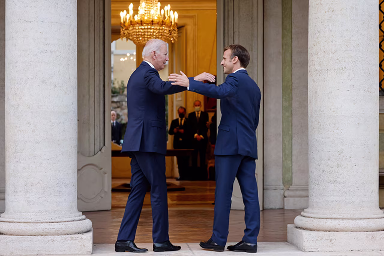 French President Emmanuel Macron (R) welcomes US President Joe Biden before their meeting at the French Embassy to the Vatican in Rome on October 29, 2021. 