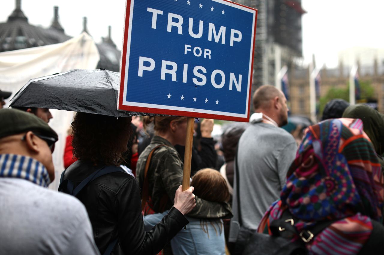 Protesters holding placards stand in the rain at Parliament Square as President Trump and first lady Melania Trump visit 10 Downing street for a meeting on June 4, 2019 in London.